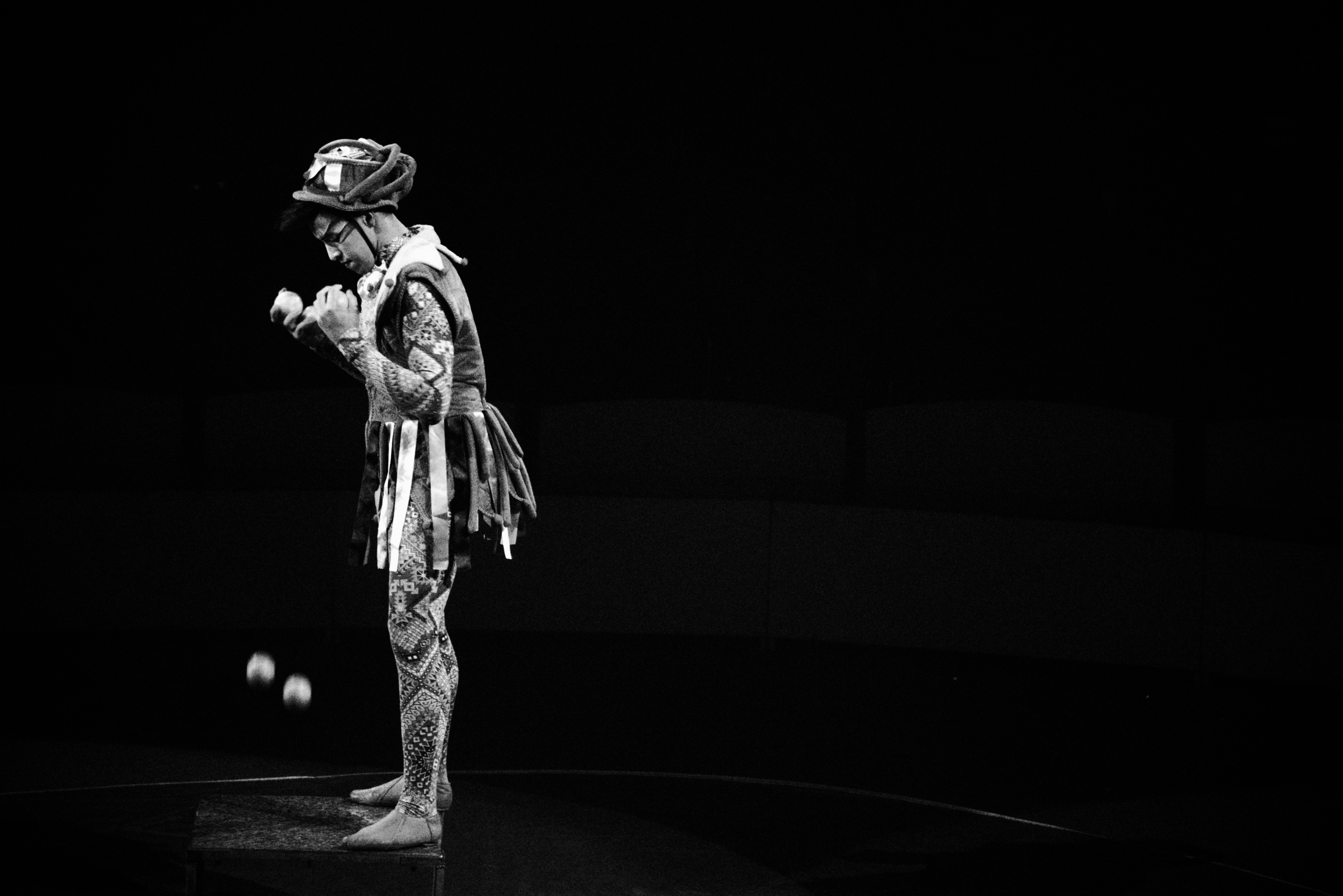 Juggler in patchwork jester costume, balls blurred in motion